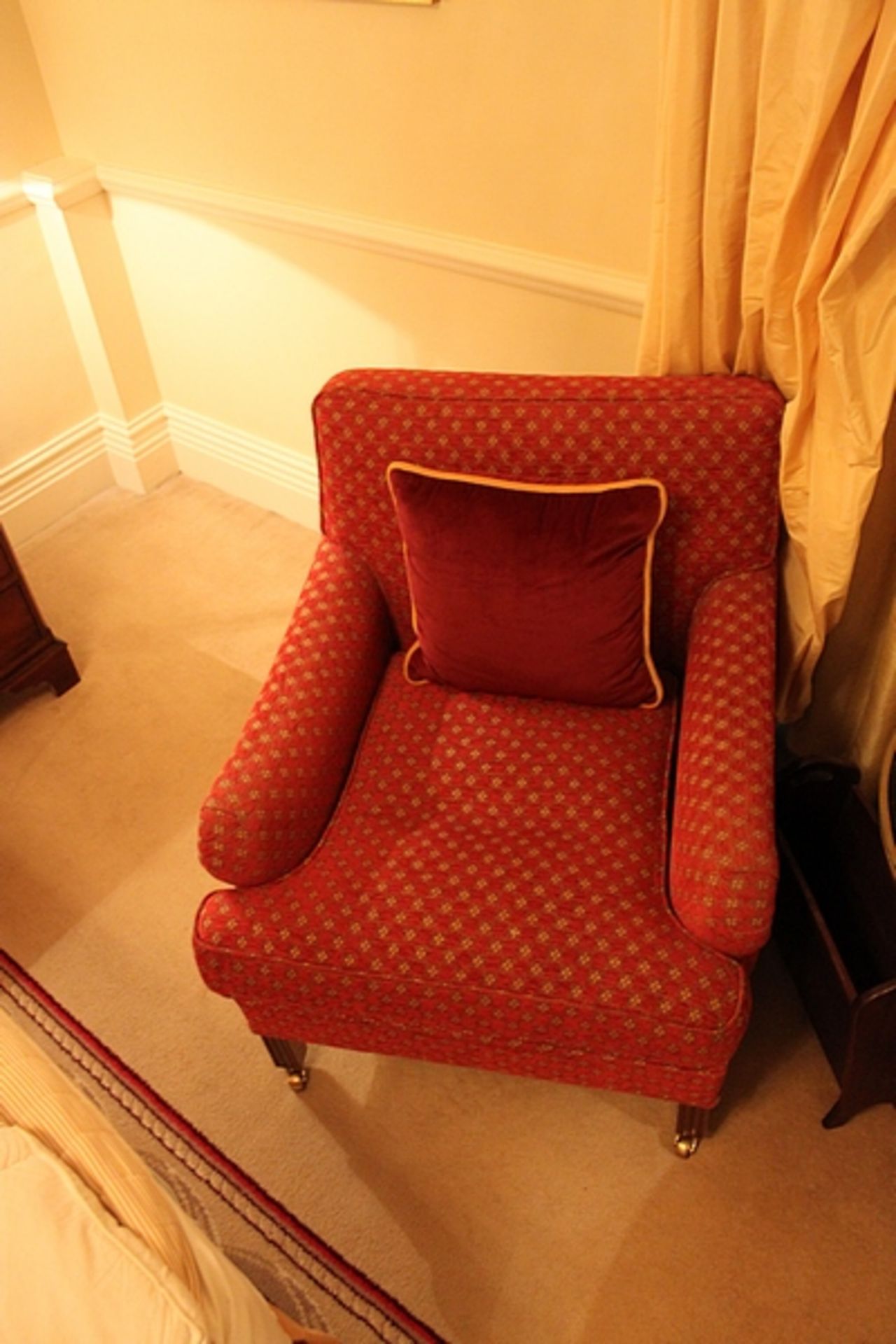 A pair of armchairs upholstered in red fabic with repeating red pattern frill base on solid