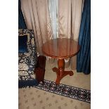 A light mahogany circular top table on carved baluster column and raised on a tri-form base with