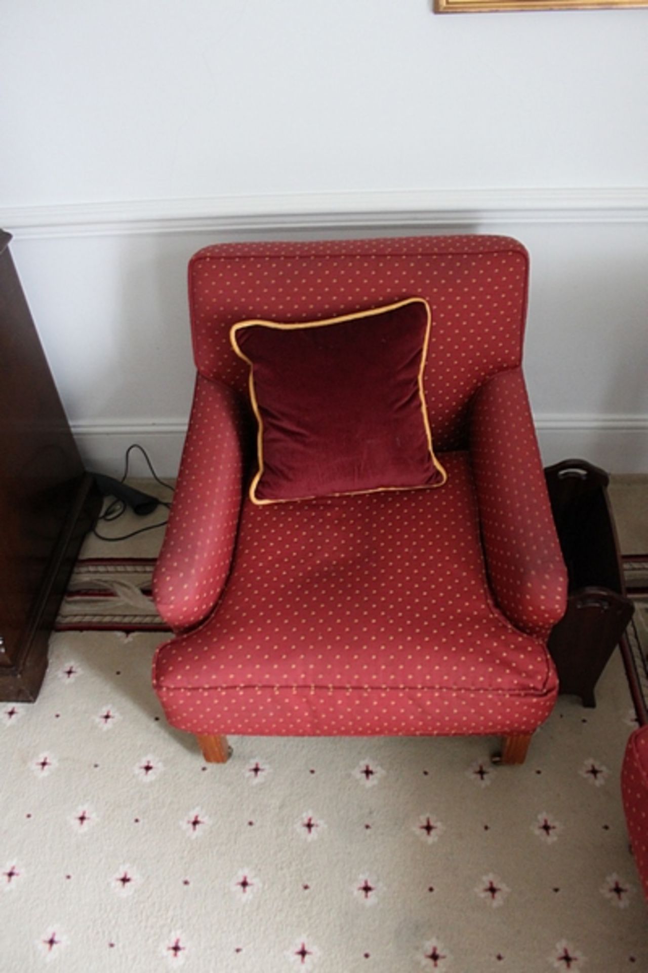 A pair of traditional easy armchairs upholstered in red with gold spot repeating pattern mounted