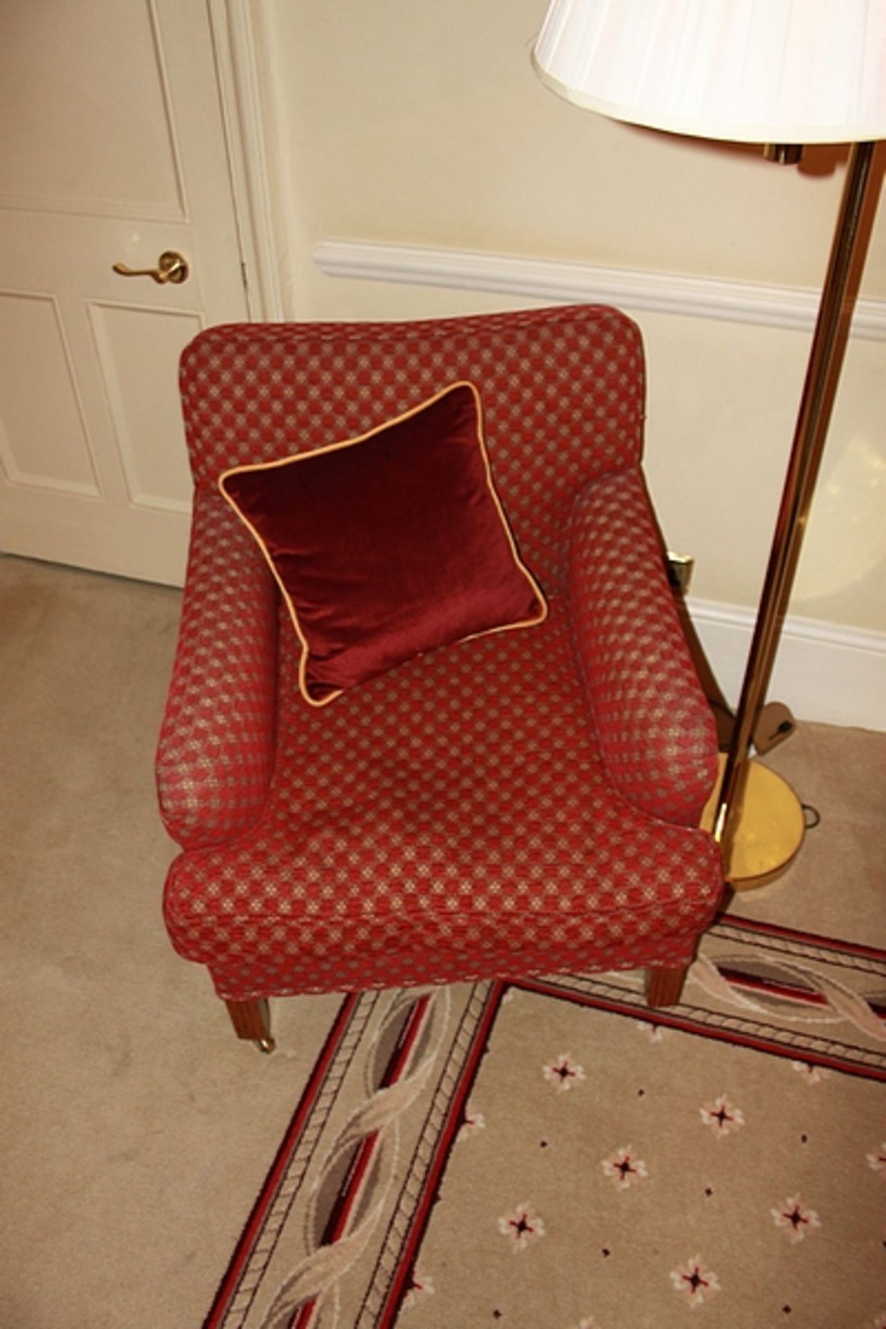 A pair of armchairs upholstered in red fabic with repeating red check pattern casters to front 700mm