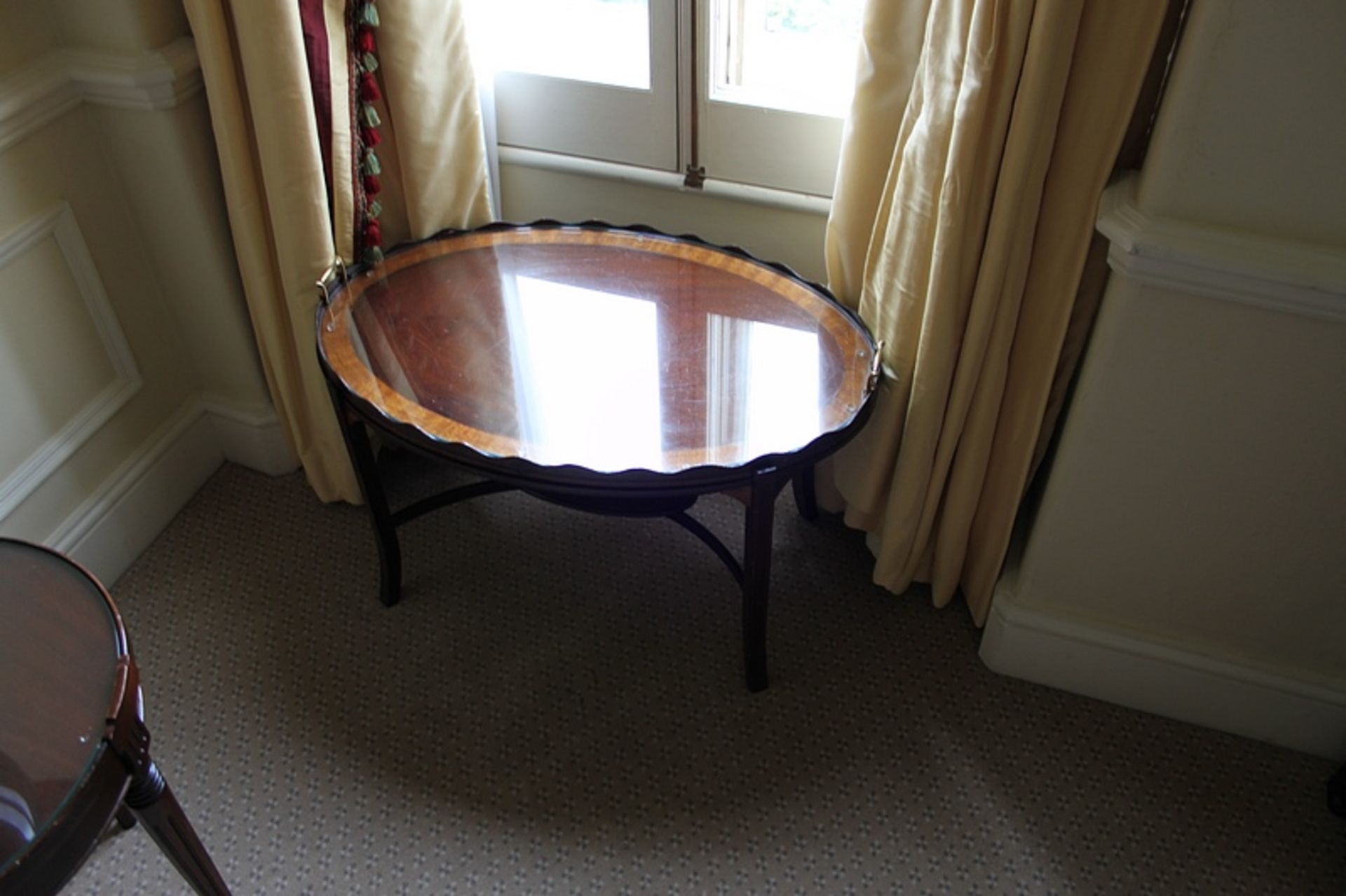 A Georgian style mahogany tray top oval table with serrated edge with central inlaid shell raised on