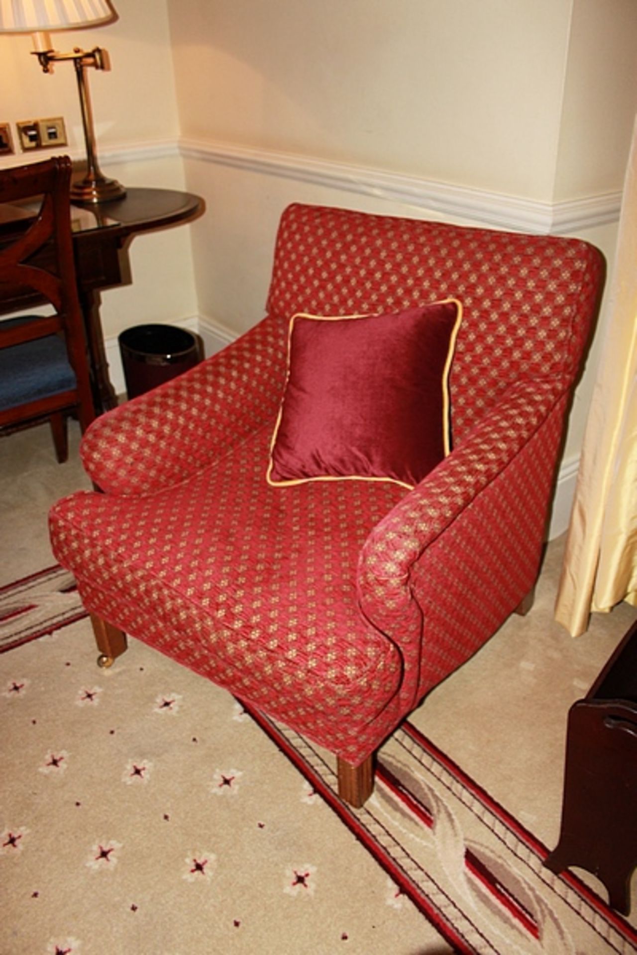 A pair of armchairs upholstered in red fabic with repeating red check pattern casters to front 700mm