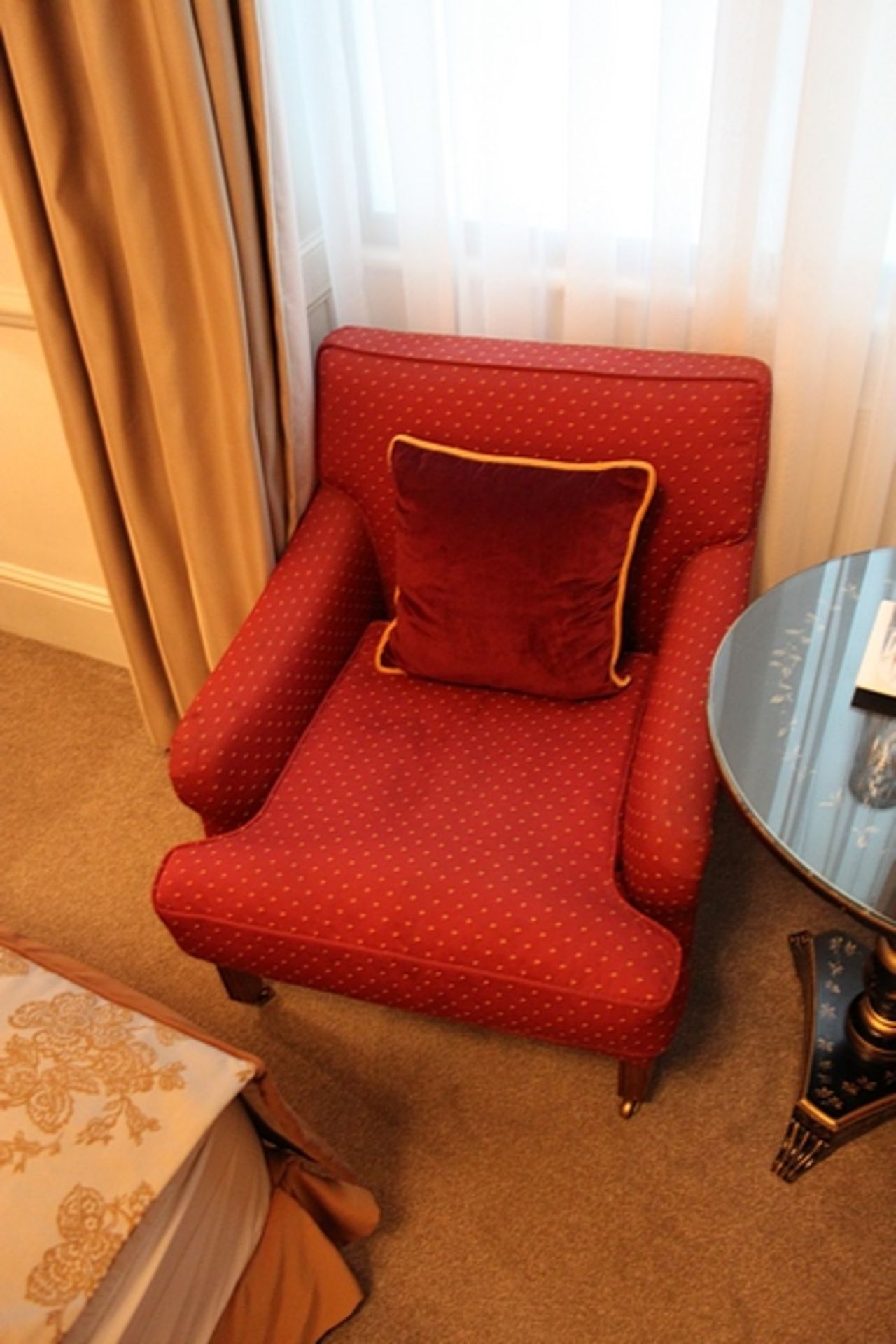 A traditional easy armchairs upholstered in red with gold spot repeating pattern mounted on solid