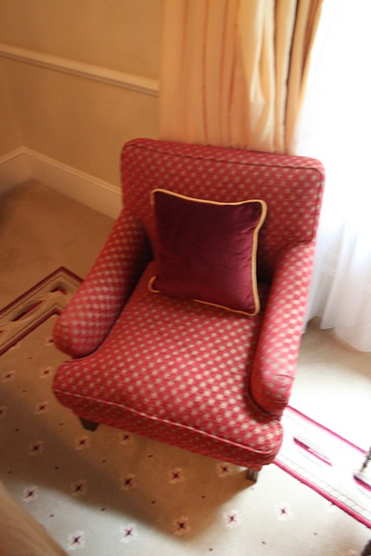 A traditional easy armchair upholstered in a red repeating pattern fabric solid legs 700 x 800mm