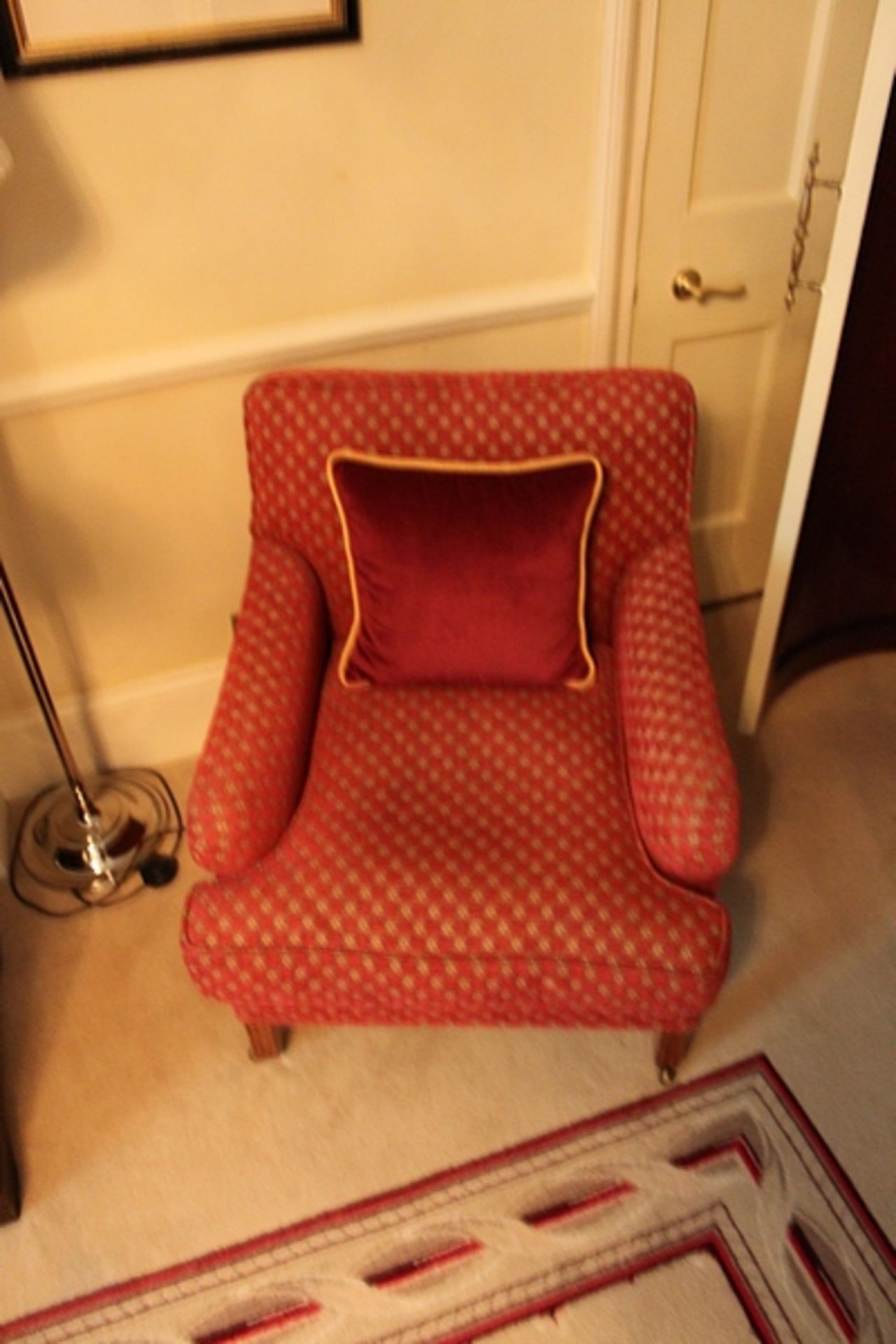 A pair of armchairs upholstered in red fabic with repeating red check pattern caster to front