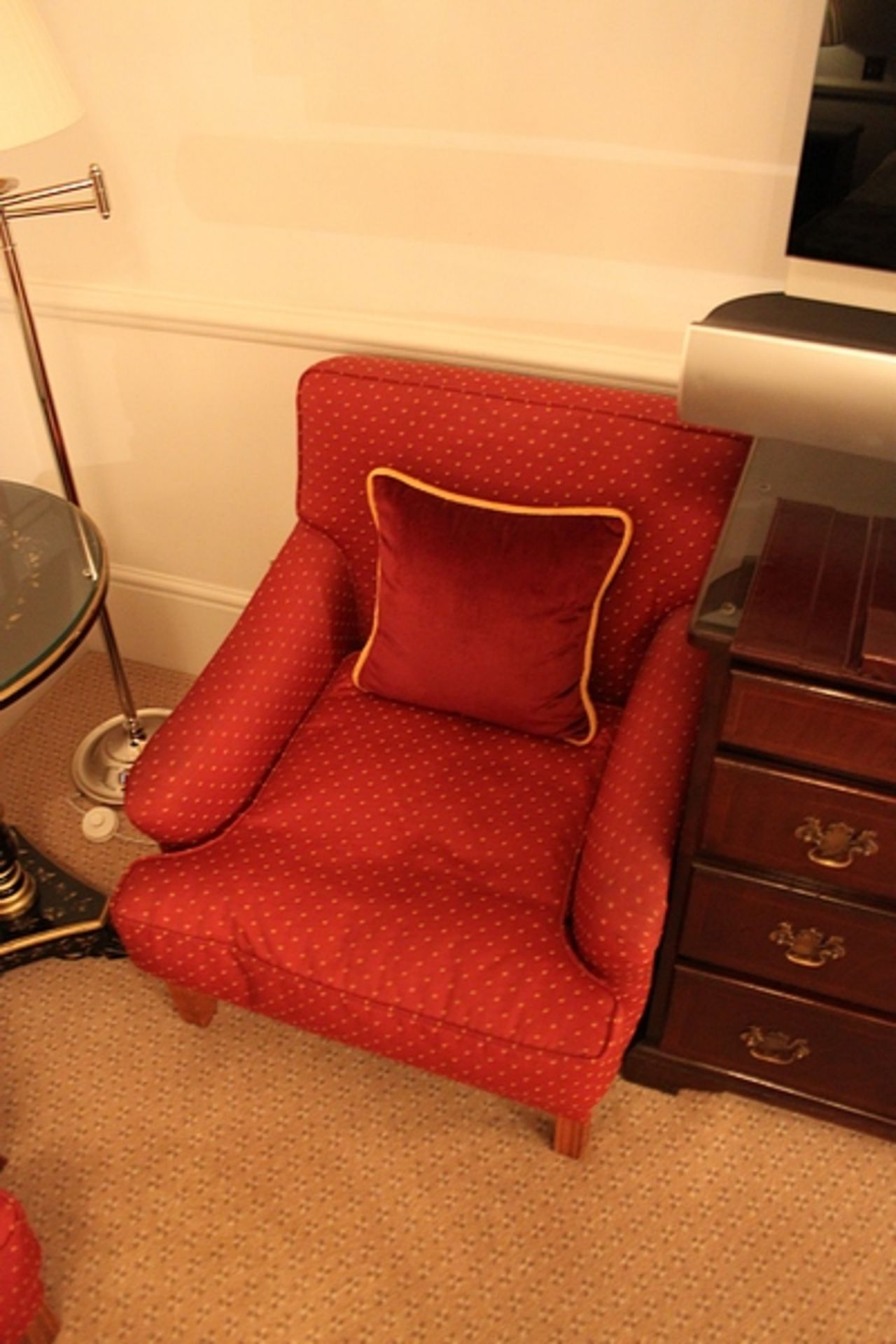 A pair of traditional easy armchairs upholstered in red with gold spot repeating pattern mounted