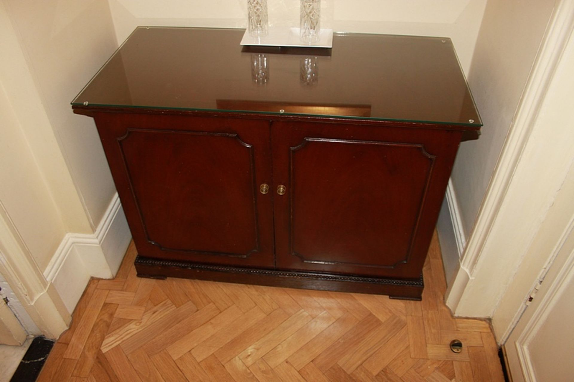 A mahogany moulded top two door side cabinet the door panel with a faux drawer frontage internally