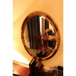 A mahogany oval carved wood bevel mirror with antiqued accents to the floral relief