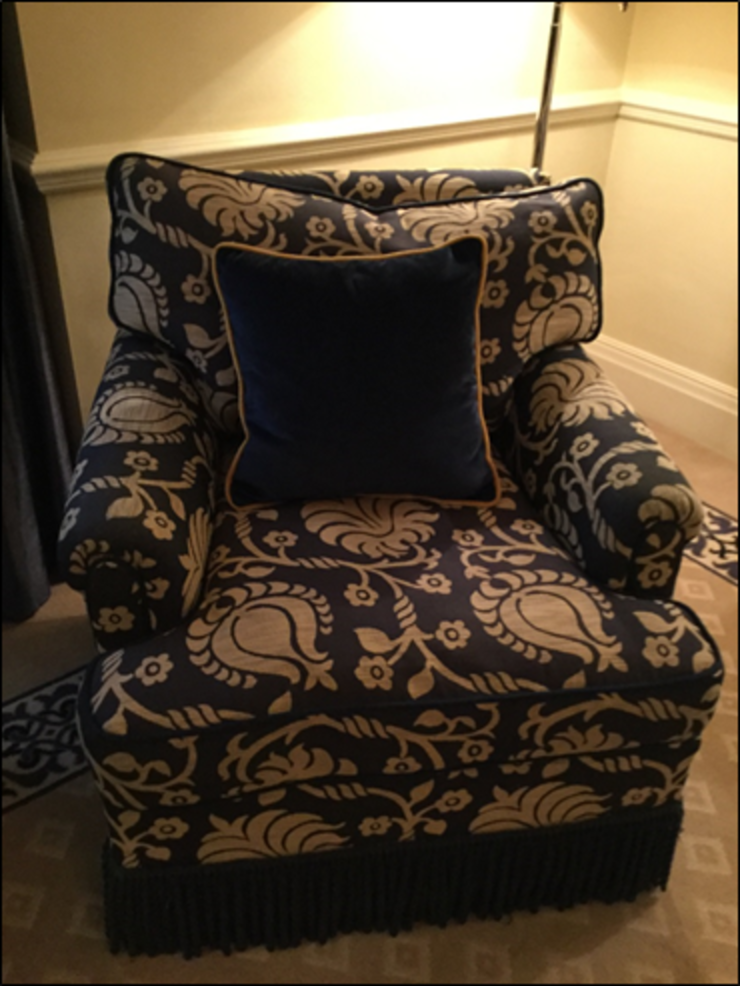 A traditional easy narrow armchair upholstered in a blue broccade fabric with frill base