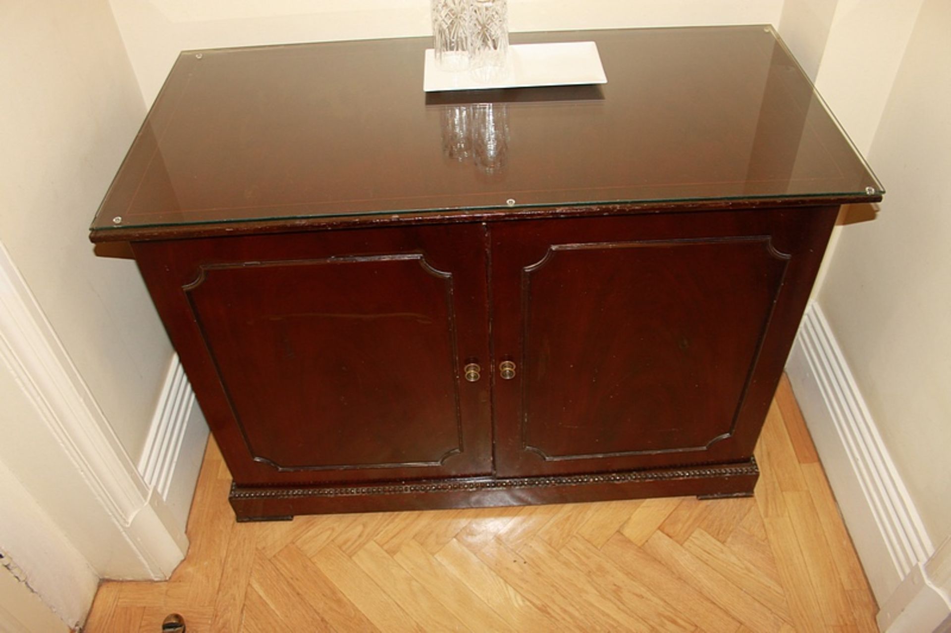 A mahogany moulded top two door side cabinet the door panel reveals internally fitted with two