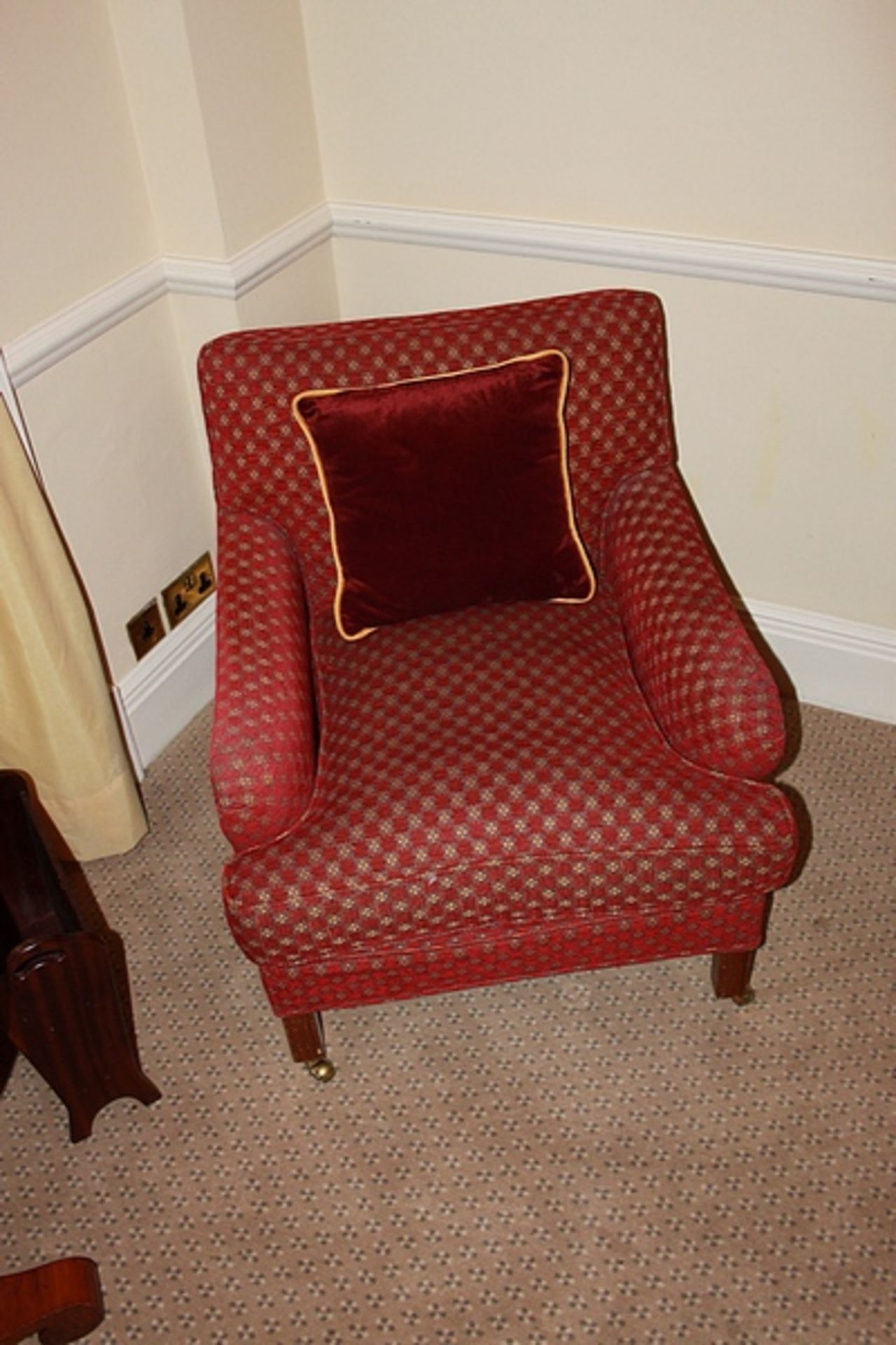 A pair of armchairs upholstered in red fabic with repeating red check pattern casters to front 700mm