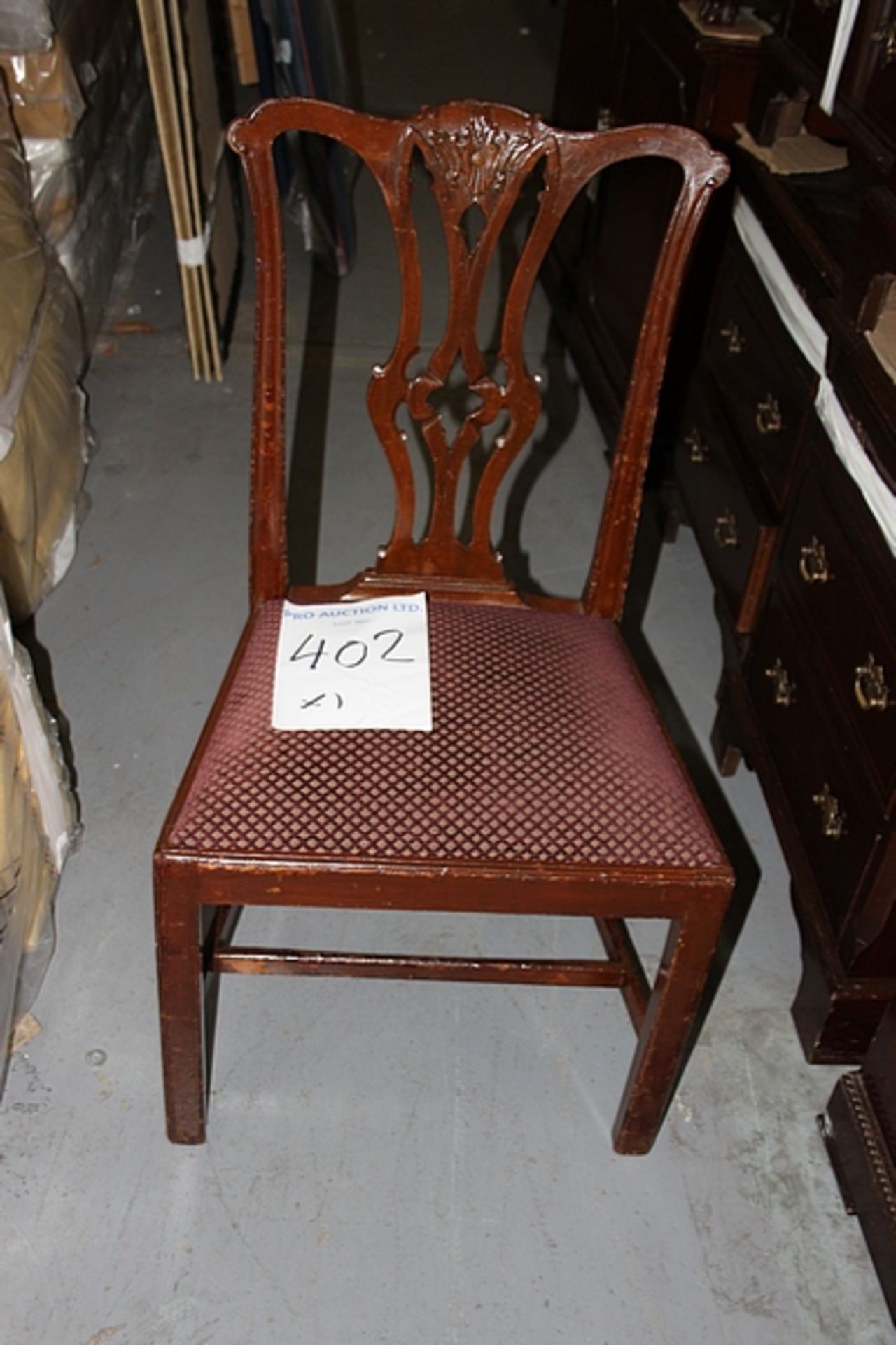 A mahogany side chair with a red and gold seat pad intricate carved back rest