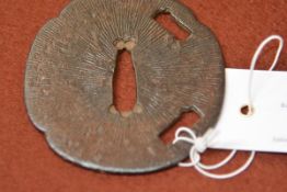 A Japanese iron tsuba, of shaped circular form, with incised decoration of radiating lines. 7.75cm