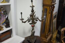 A late 19th century patinated metal figural three-light lamp, cast as partially-clad Eve on a