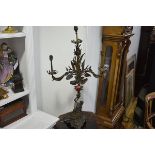 A late 19th century patinated metal figural three-light lamp, cast as partially-clad Eve on a