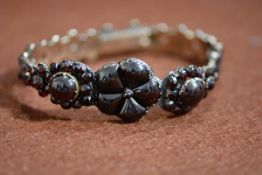 An Edwardian yellow metal garnet encrusted articulated bracelet, restored and missing pin, gross