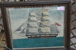 A 19th century woolwork picture of a twin-masted ship in full sail, flying the Royal Navy Ensign,