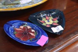Two Moorcroft pottery ashtrays, the first triangular, Honeysuckle pattern against a blue ground,
