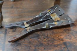 A pair of late 19th century mahogany folding boot jacks enclosing two steel pulls with button hooks.