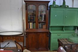 A mid-Victorian mahogany bookcase cabinet, the upper section with a moulded cornice above a pair