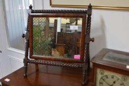 An early 19th century mahogany toilet mirror, the rectangular plate swivelling within a spirally