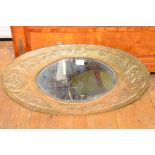 An Art Nouveau brass mirror in the Glasgow style, oval, repousse with Celtic knots. 76cm by 37cm