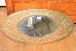 An Art Nouveau brass mirror in the Glasgow style, oval, repousse with Celtic knots. 76cm by 37cm