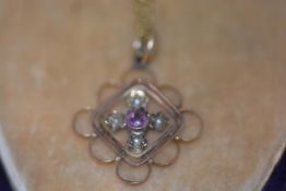 An Edwardian amethyst and seed pearl set pendant, centred by a round-cut amethyst in a lozenge