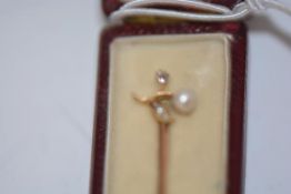 A diamond and seed pearl set 15ct gold stick pin, early 20th century, the terminal modelled as a