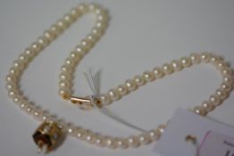 A single strand cultured pearl necklace, the uniform pearls suspending an enamel and pearl drop