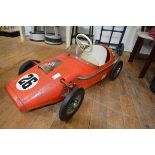 A 1960's Tri-ang pedal toy racing car, in red, with decals