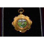 A 9ct gold and enamel Rugby Union medal, decorated with a running figure in coloured enamels, the