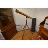 A floorstanding brass telescope in 19th century style, on a tripod base, marked "Aronsbery & Co.