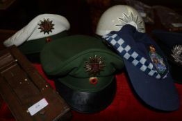 A group of modern German military caps, a helmet, a Queensland Police cap, a metal mounted rattle