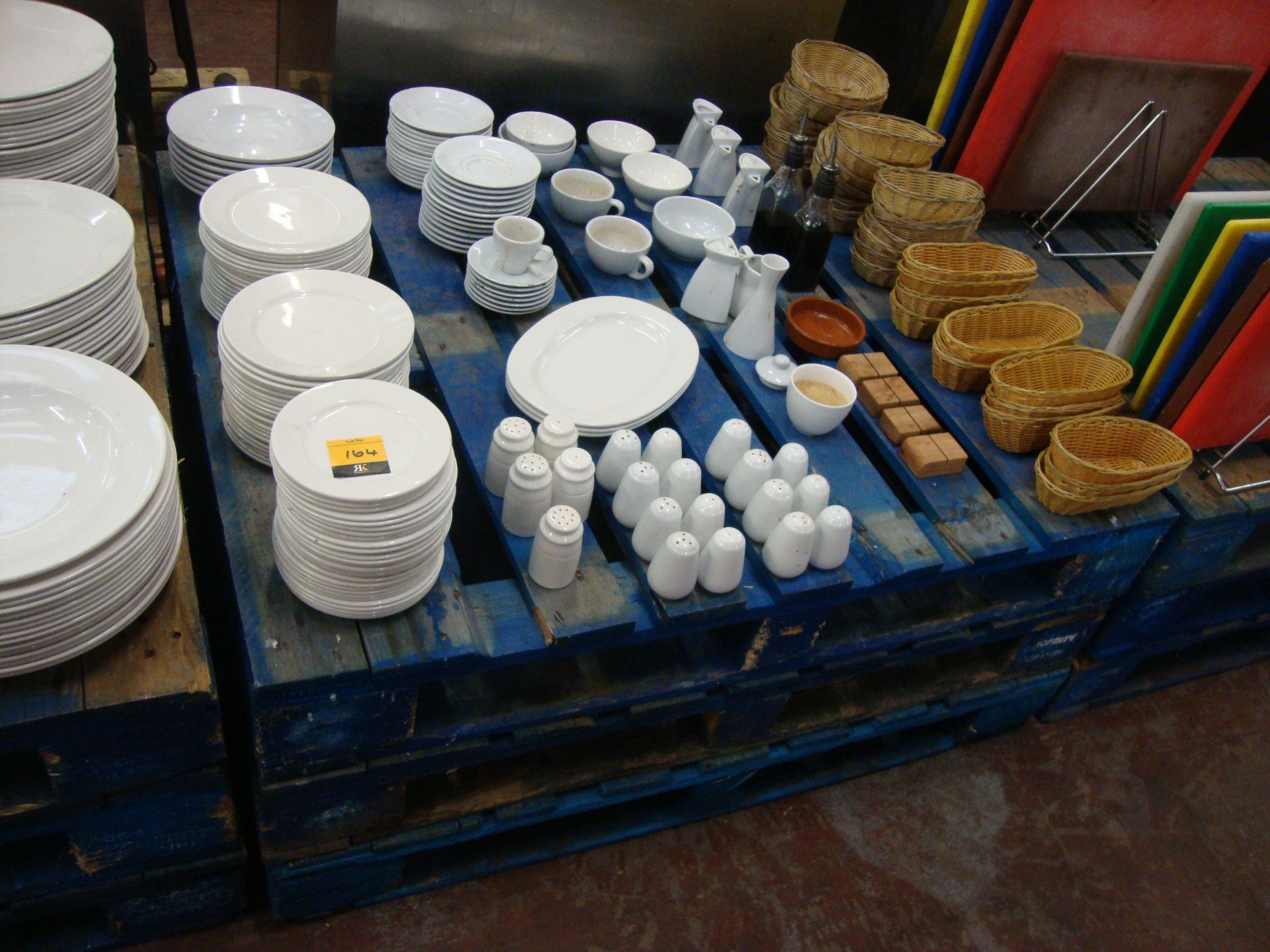 The contents of a pallet of assorted plates, cups, saucers, condiment sets, baskets & more