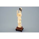 A Chinese carved ivory figure of a beauty with flowers on wooden base, early 20th C. [...]