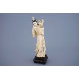 A Chinese carved ivory figure of Guanyin with a bird on wooden base, 19th C. - Dim.: [...]
