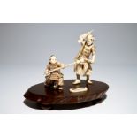 A Japanese ivory group of a warrior and his pupil, on a wooden base, Meiji, signed Dim.: 23 x 16,5