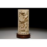 A Chinese carved ivory plaque with immortals on wooden stand, 2nd quarter 20th C. Dim.: 27,5 x 11