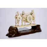 A large Japanese ivory okimono of boys playing a drum on a carved wooden base, Meiji, late 19th