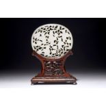 A Chinese reticulated jade plaque, on wooden stand, 19th C. Dim.: 7 x 6 cm (the plaque)H.: 10,5