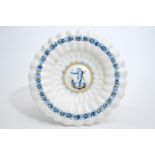 A Dutch Delftware gadrooned dish with a putto in blue and yellow, Haarlem, 17th C. Dia.: 33 cm