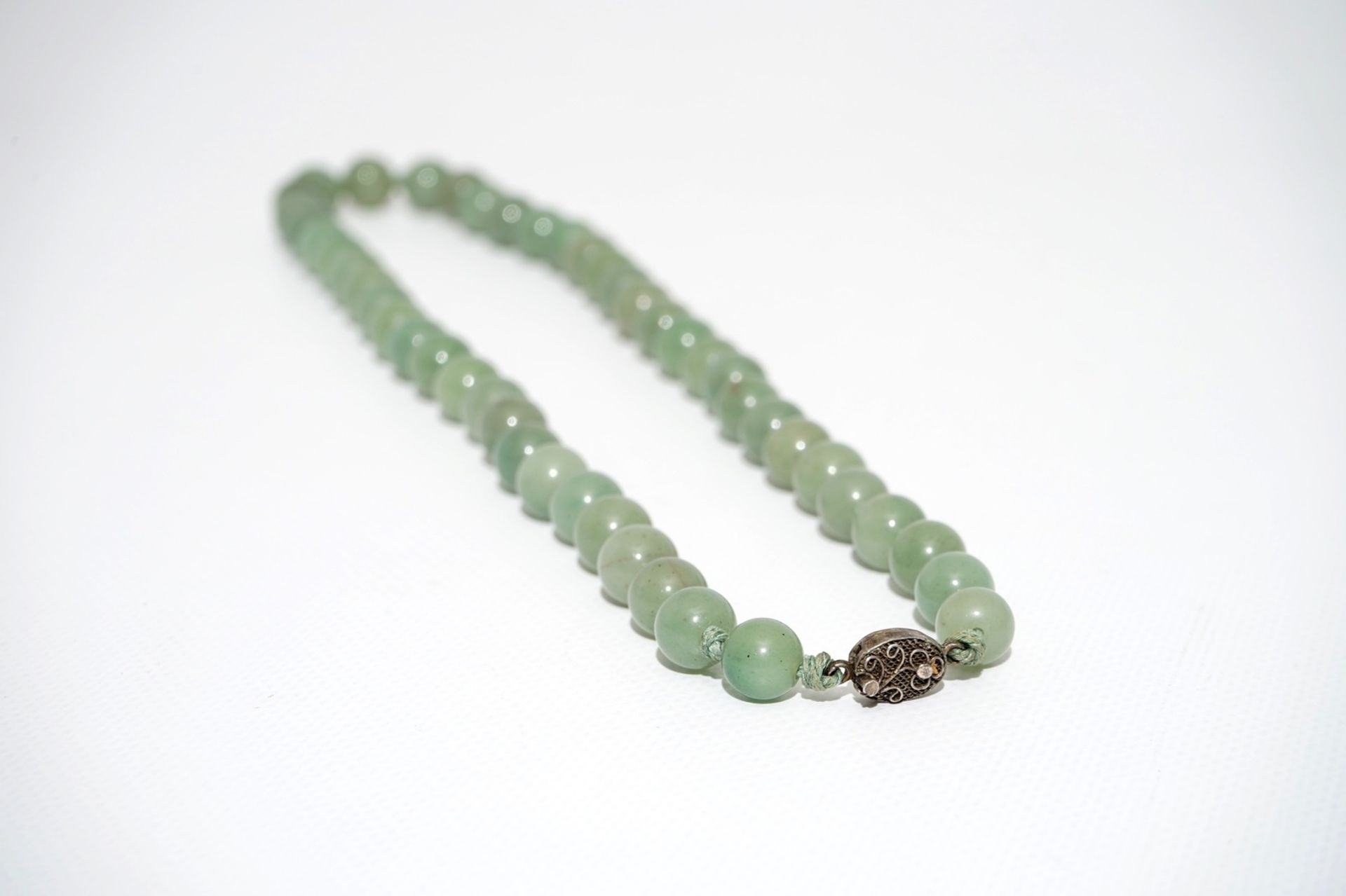 A Chinese green jade beads necklace with silver lock, 19/20th C. - Image 4 of 5