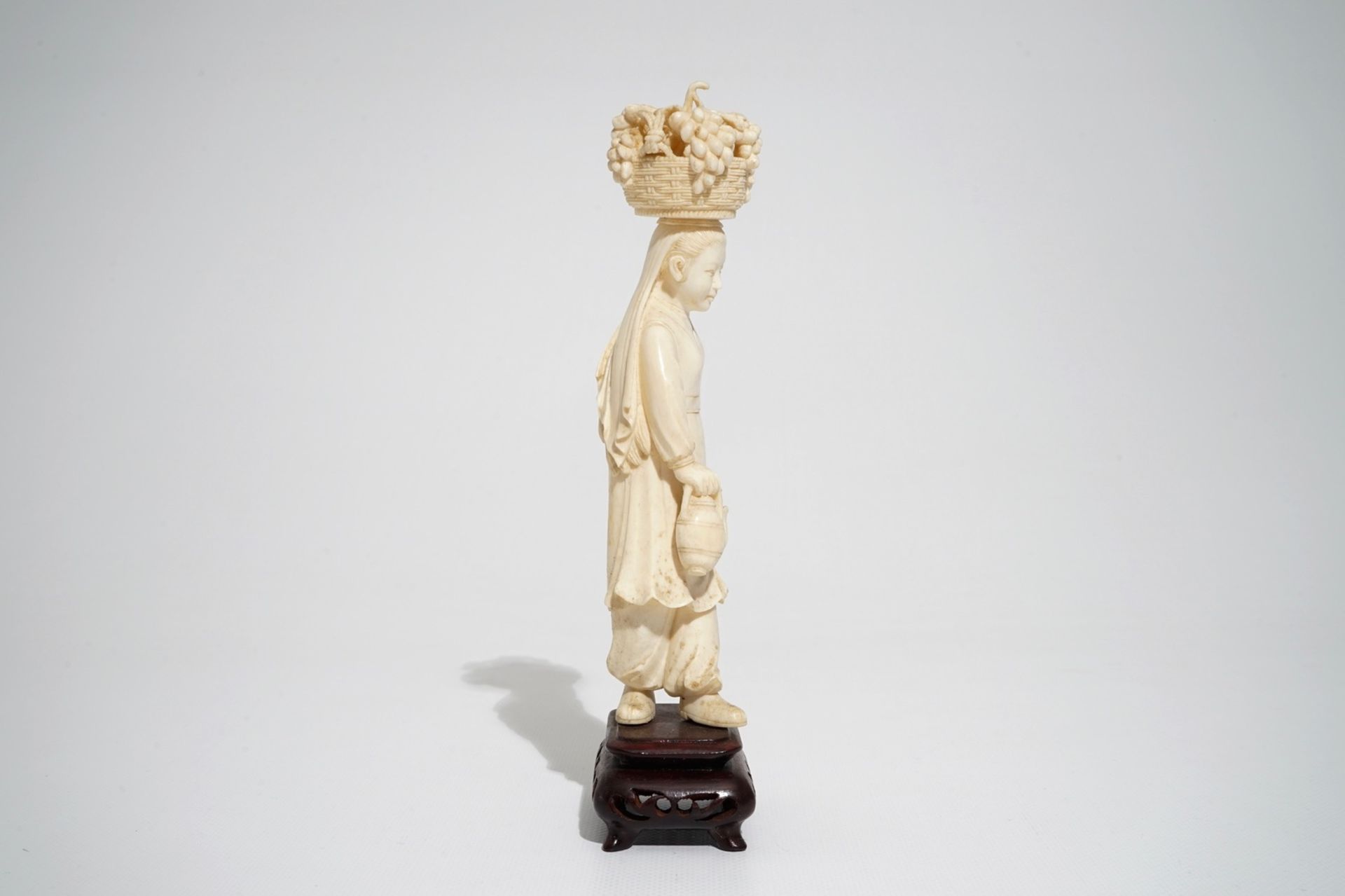 A Chinese carved ivory figure of a lady with a fruit basket, 2nd quarter 20th C. - Image 5 of 7