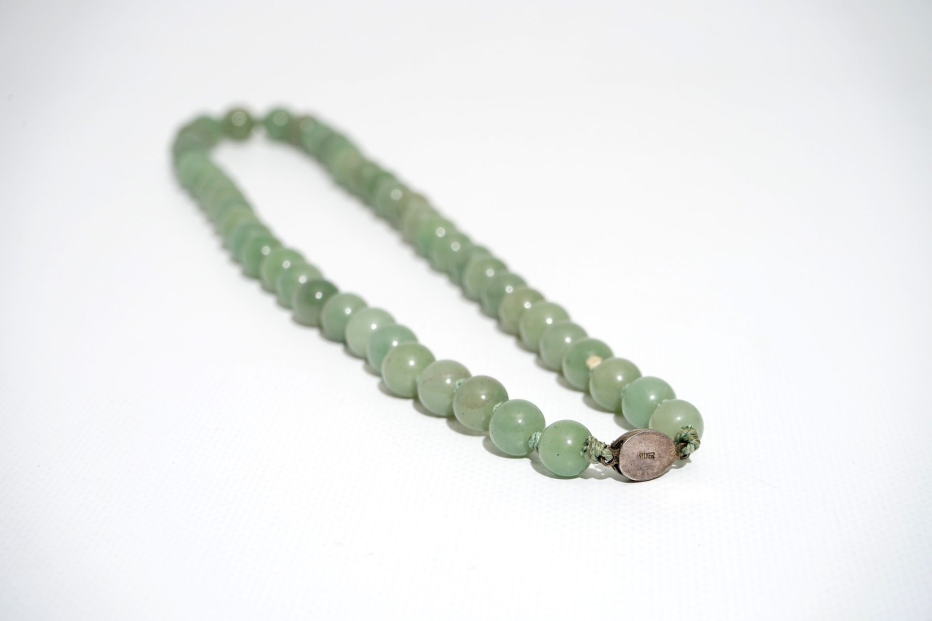 A Chinese green jade beads necklace with silver lock, 19/20th C. - Image 5 of 5