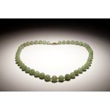 A Chinese green jade beads necklace with silver lock, 19/20th C.