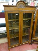 AN EARLY 20th CENTURY OAK BOOKCASE with fan carved arched top decoration, twin leaded glass doors