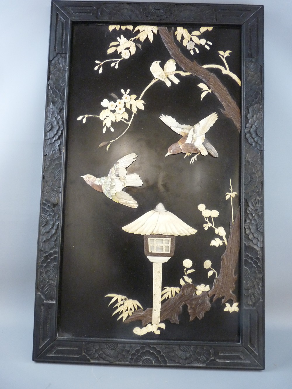 AN ORIENTAL SHIBAYAMA PANEL of birds and blossom over a thatched birdhouse set in a carved