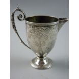 A VICTORIAN SILVER CREAM JUG with bright cut floral decoration and a long scrolled handle to a short