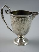 A VICTORIAN SILVER CREAM JUG with bright cut floral decoration and a long scrolled handle to a short